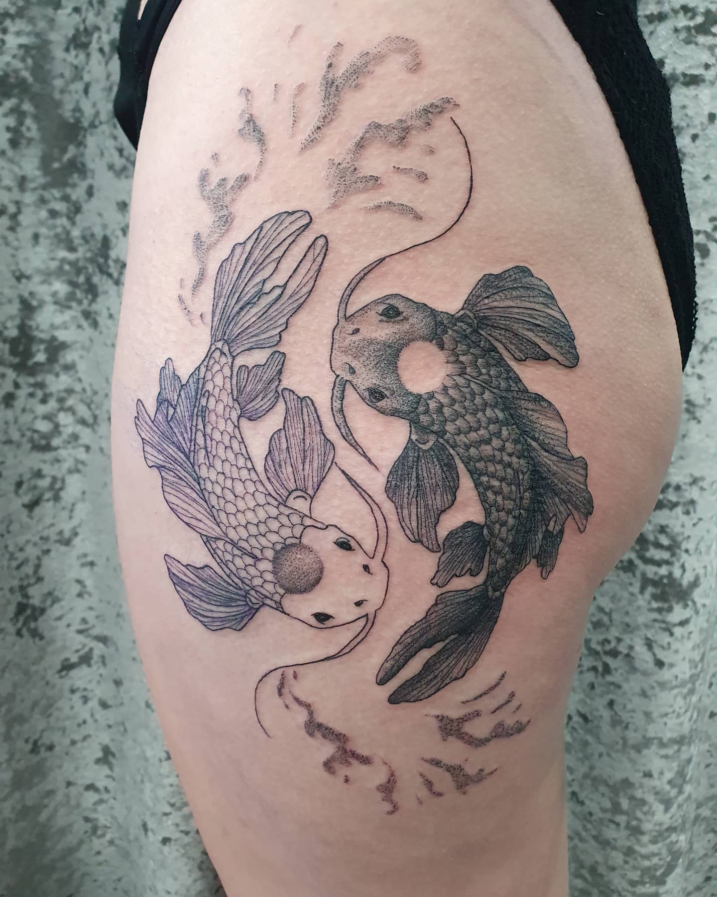 Tattoo of two koi fish circling each other on the upper thigh